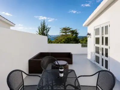 Mesita y sillas en la terraza blanca de la azotea, con asientos de descanso detrás