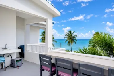 Barra y banquetas de la azotea junto al fregadero exterior, con baranda blanca, palmas y el Atlántico al frente