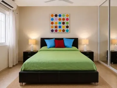 Segunda habitación con colcha verde, almohadas de colores y puertas de clóset con espejos