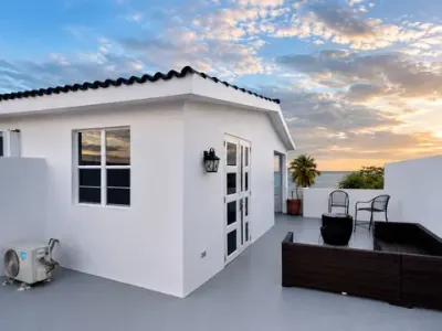 Terraza en la azotea bajo un cielo amplio: paredes blancas, cuarto de la azotea y mar a un lado